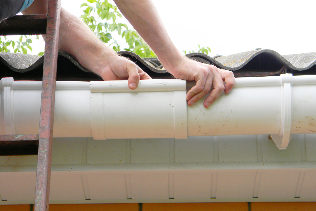 Contractor installing plastic roof gutter pipeline